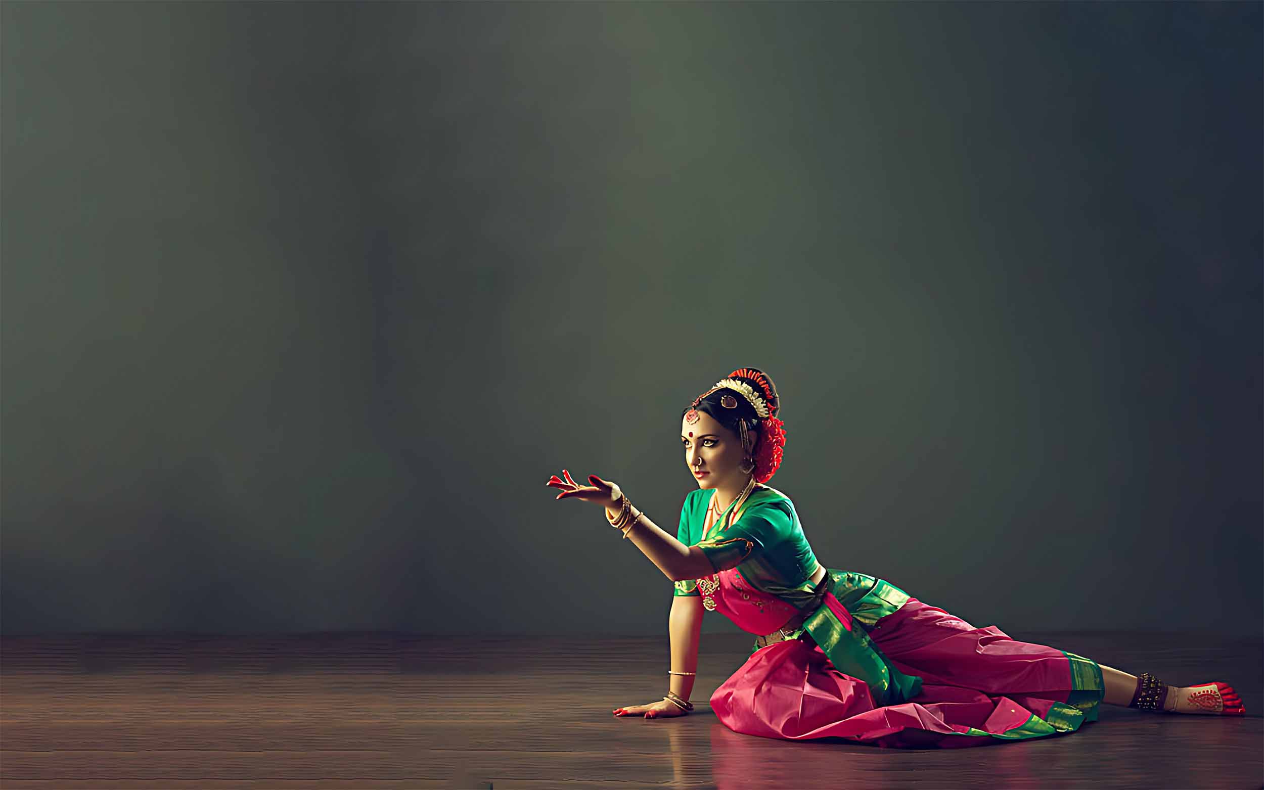 Kairali Arts Centre - Bharatanatyam classical dancer in green and pink silk, hand raised in a graceful mudra. Indian classical dance and music school in Sharjah, UAE.