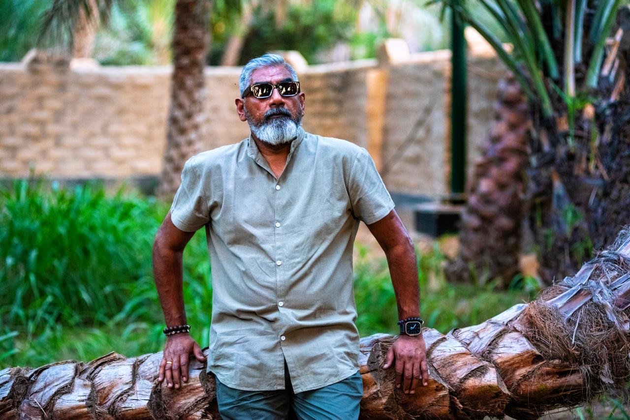 Full-length outdoor portrait of Dinesh in a garden setting