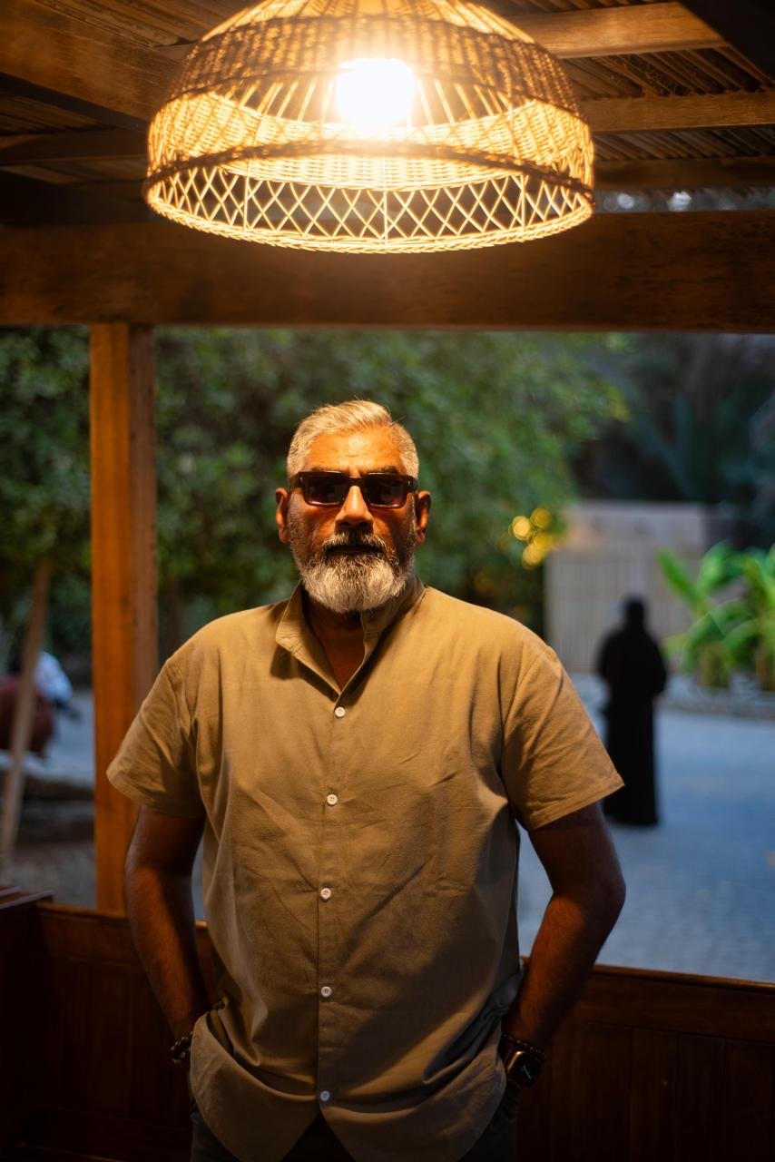 Dinesh standing beneath a handcrafted lamp in warm evening light